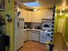 Kitchen featuring a skylight, white appliances, decorative backsplash, light countertops, and a baseboard radiator