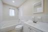 Full bathroom with vanity, shower / bath combination, tile walls, light tile patterned floors, and wainscoting