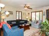 Living area with a ceiling fan, ornamental molding, wood finished floors, and an AC wall unit