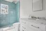 Full bathroom featuring a tile shower, visible vents, toilet, and vanity