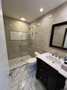 Spa-inspired primary bathroom featuring a frameless glass-enclosed walk-in shower with subway tile surround and pebble stone flooring, dual vanity wit