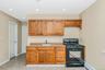 Kitchen featuring black range with gas cooktop, light countertops, brown cabinetry, a baseboard radiator, and recessed lighting