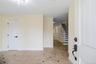 Inviting entryway featuring light-toned tile flooring with dark accent tiles, a white paneled door with matte black hardware, and a grand staircase wi