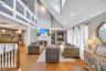 Vaulted ceiling living area featuring a stone surround fireplace, hardwood flooring, recessed lighting, and a built-in display cabinet