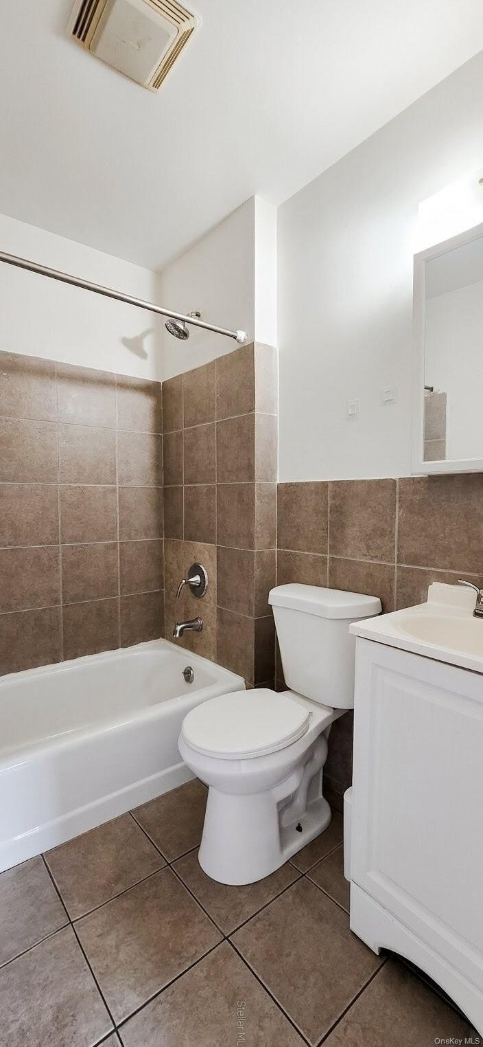 Full bathroom featuring a white bathtub, toilet, and vanity with an integrated sink
