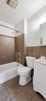 Full bathroom featuring a white bathtub, toilet, and vanity with an integrated sink