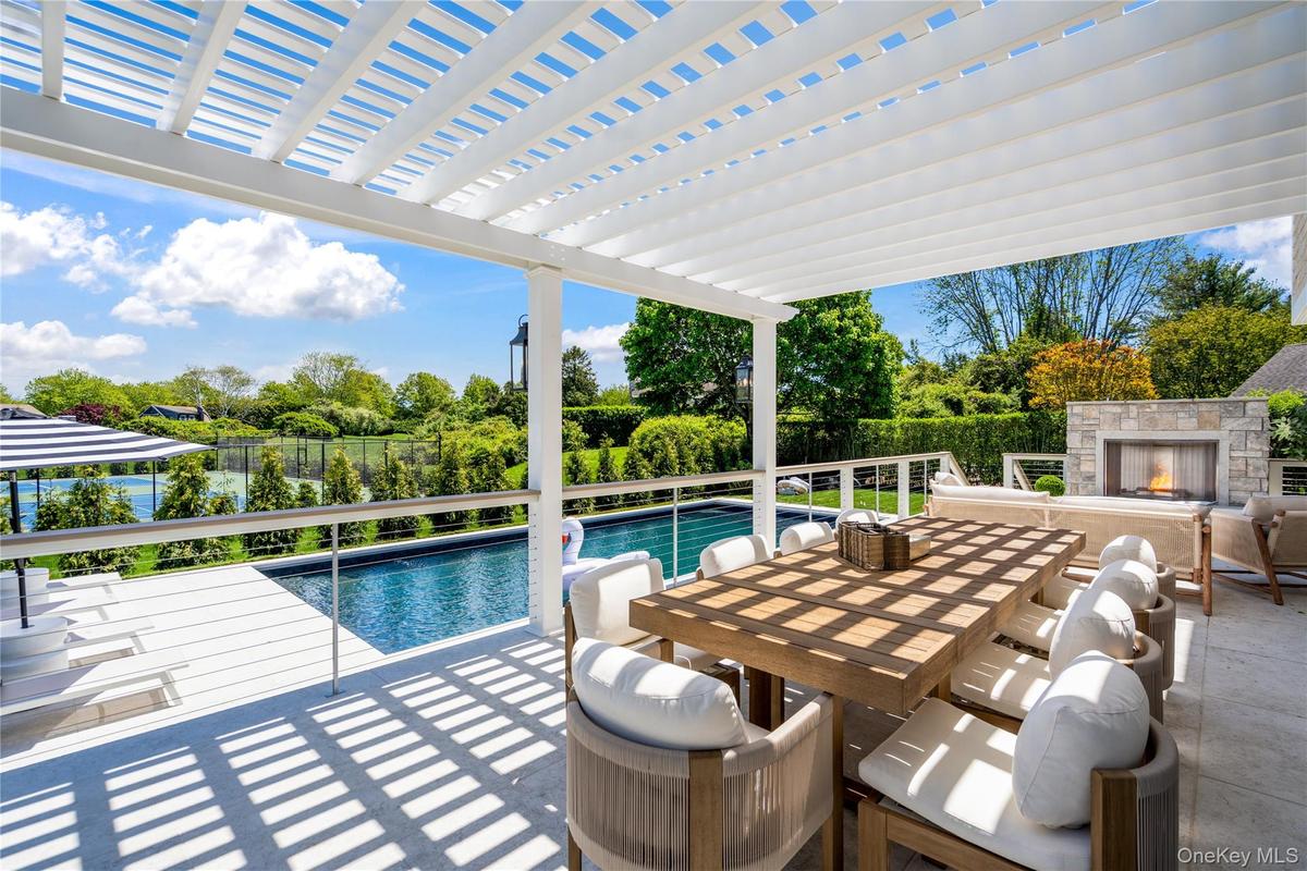 View of swimming pool featuring an outdoor stone fireplace, outdoor dining space, a pergola, and a patio