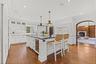 Bright, chef's kitchen featuring custom white cabinetry, marble backsplash, and a spacious center island with seating—perfect for entertaining and eve