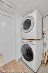 Dedicated laundry area featuring stacked appliances and wood-finish flooring