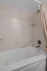 Jetted tub/shower combo in primary suite. A small storage area is just behind.