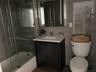 Bathroom with bath / shower combo with glass door, tile walls, vanity, backsplash, and dark tile patterned flooring