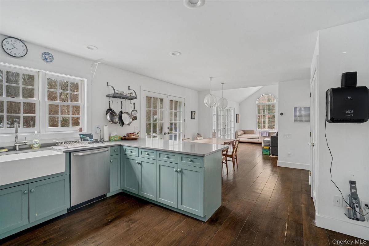 Kitchen featuring a peninsula, stainless steel dishwasher, hanging light fixtures, and light stone countertops