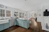 Kitchen featuring a peninsula, stainless steel dishwasher, hanging light fixtures, and light stone countertops