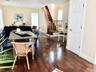 Open-concept living area featuring rich wood-finish flooring, a dining table with seating for multiple guests, and a striking wooden staircase with me