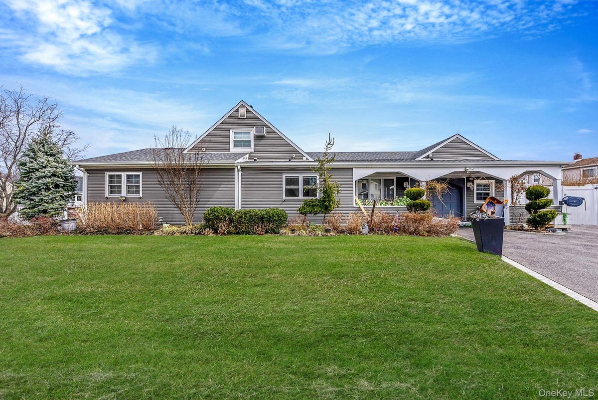 View of front of house with a front yard and a shingled roof