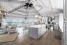 Kitchen featuring stainless steel appliances, open floor plan, dark wood-style floors, wall chimney range hood, and gray cabinets