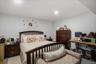 Spacious bedroom and bath on lower level featuring light-toned walls and ceiling, recessed lighting, and durable flooring with a den area with a kitch