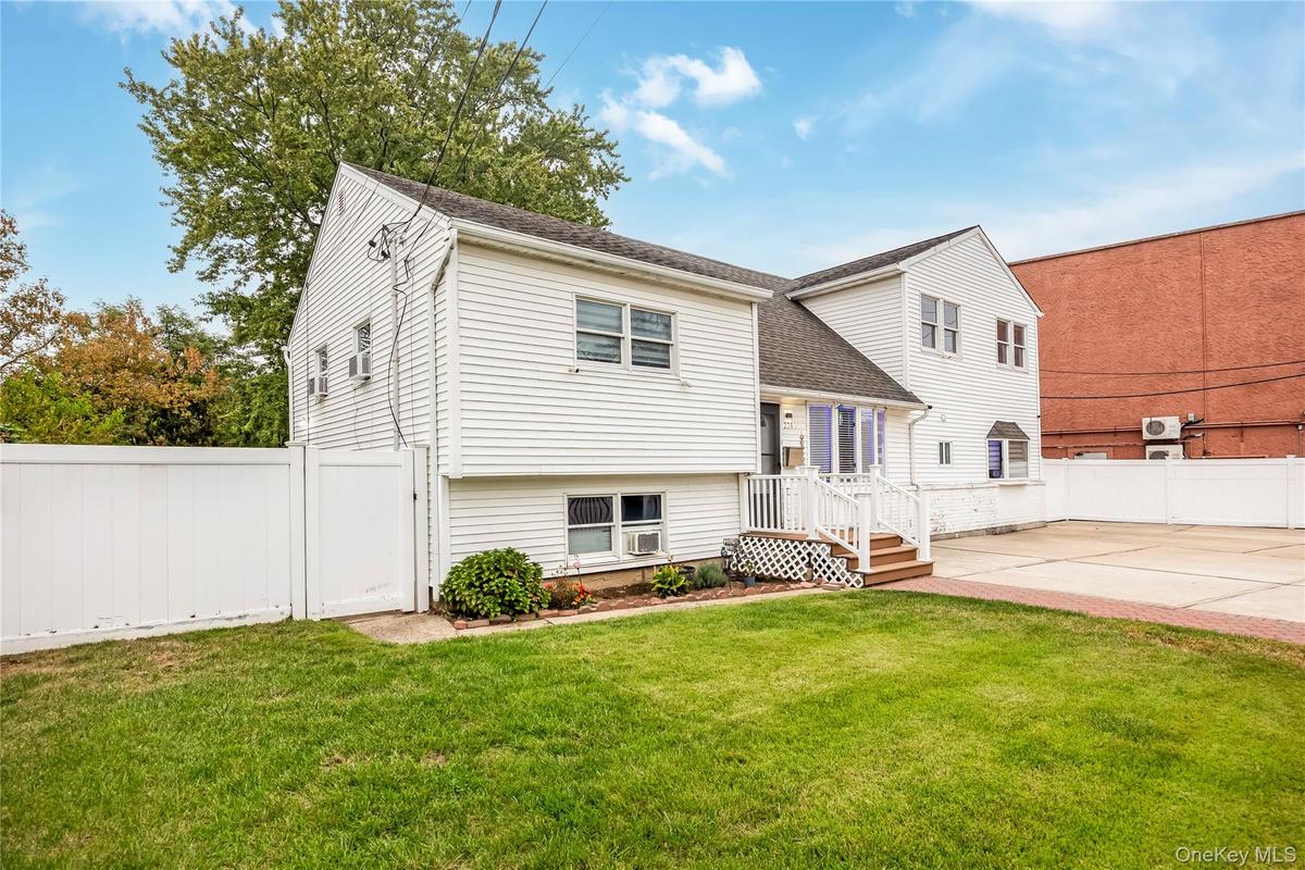 View of front of home with a fenced backyard, a shingled roof, and a patio area
