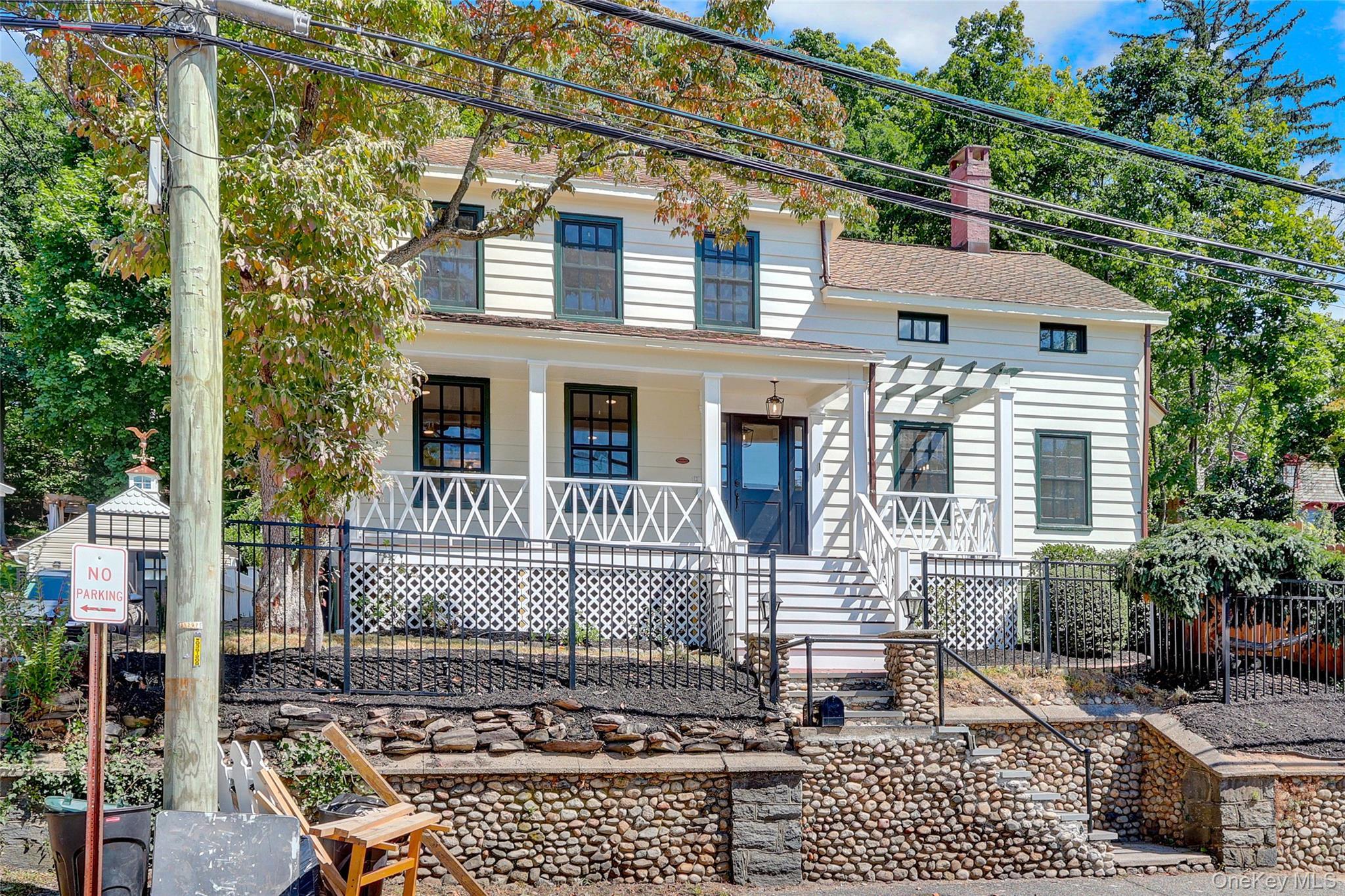 View of front of home featuring a chimney, a porch, stairway, and a shingled roof