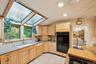 Kitchen with tasteful backsplash, light brown cabinetry, light stone countertops, a skylight, and vaulted ceiling
