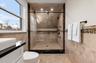 Full bath featuring tile walls, a stall shower, vanity, and a wainscoted wall