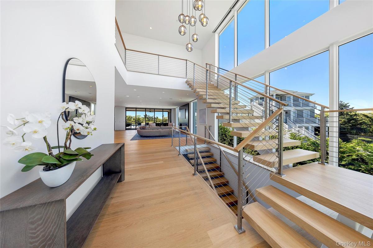 Staircase with a high ceiling, wood finished floors, a chandelier, and recessed lighting