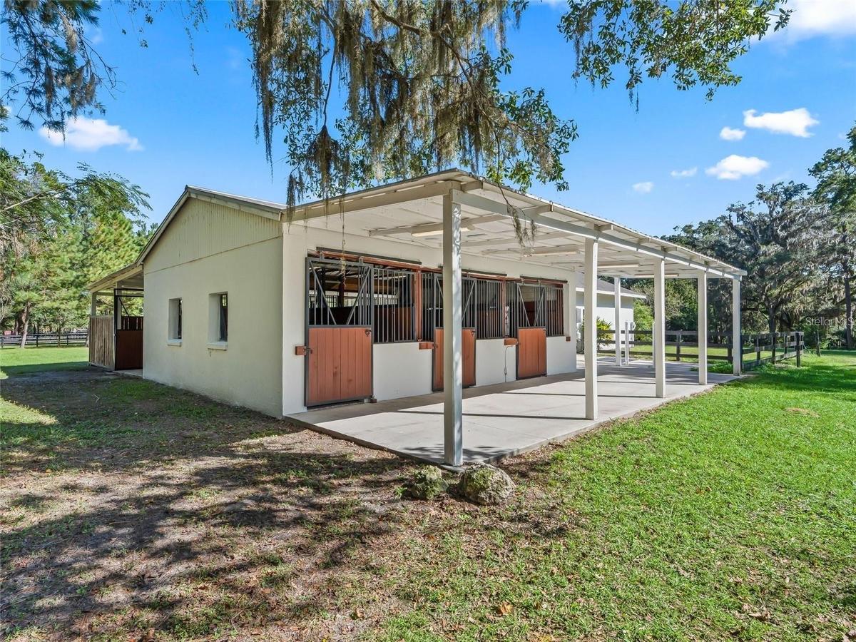 Well-maintained horse barn featuring spacious stalls and a covered work area.