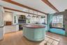 Kitchen with green cabinetry, plenty of natural light, white cabinets, hanging light fixtures, and beamed ceiling