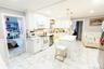 Kitchen featuring a wainscoted wall, crown molding, white appliances, white cabinetry, and light marble finish flooring