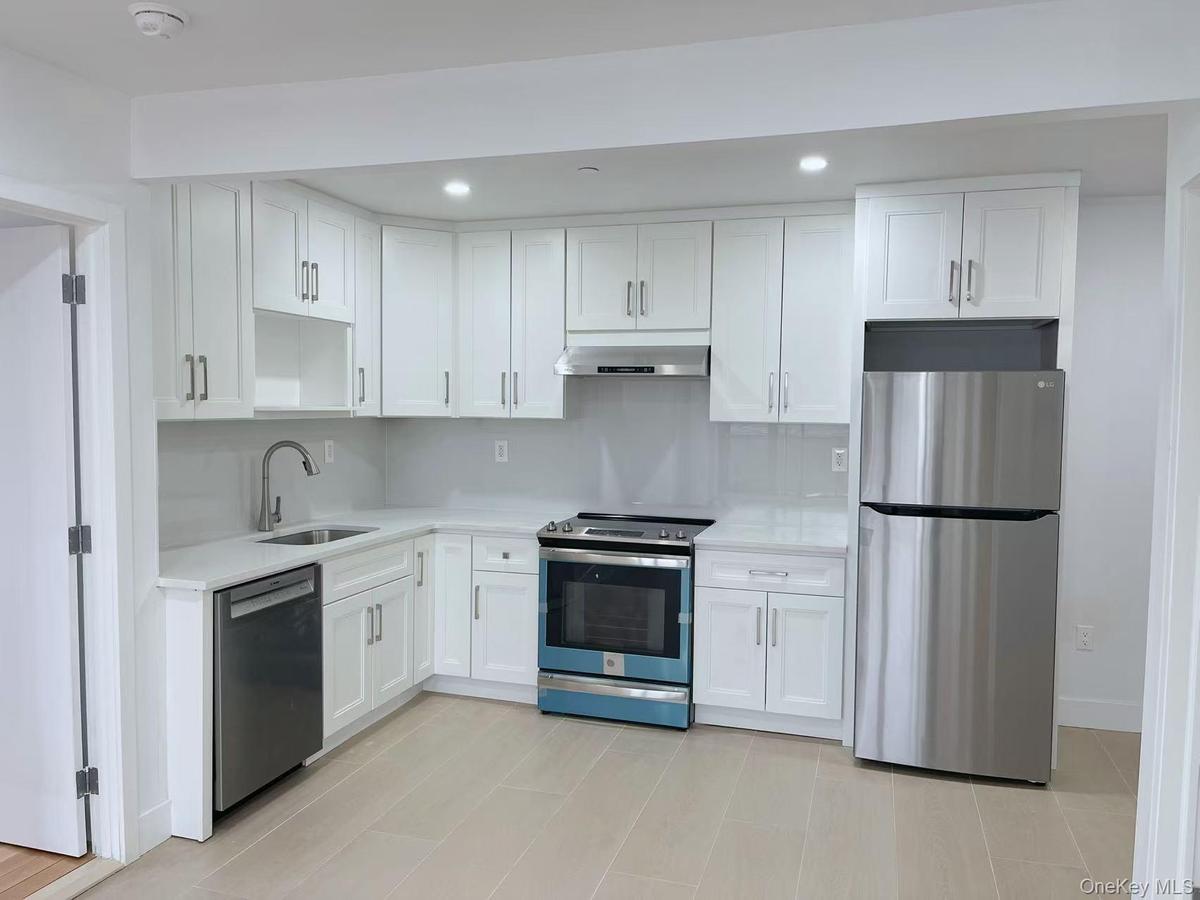 Kitchen with stainless steel appliances, white cabinetry, recessed lighting, extractor fan, and light stone counters