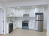 Kitchen with stainless steel appliances, white cabinetry, recessed lighting, extractor fan, and light stone counters
