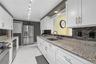 Galley kitchen with expansive white cabinetry, granite counters and updated appliances