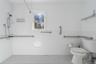 Bathroom with tile walls, a wainscoted wall, toilet, and tiled shower