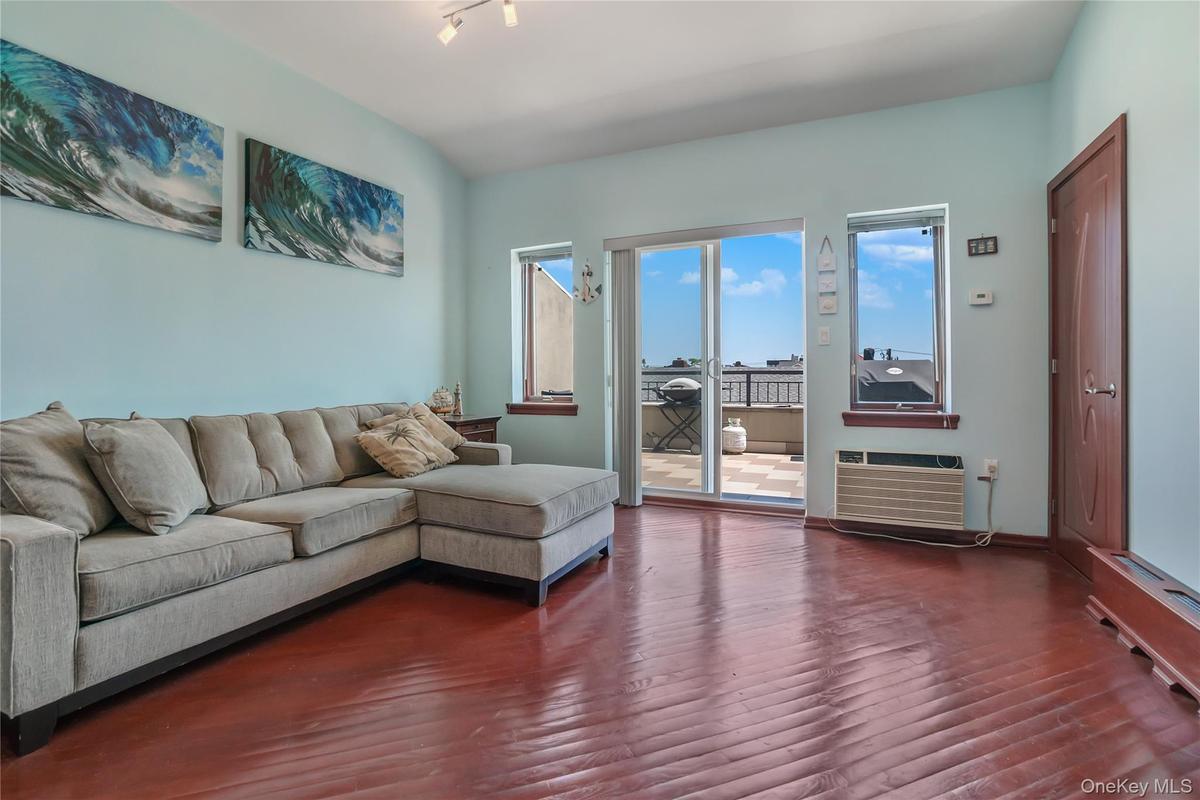 Living area featuring dark wood-style floors and a wall mounted air conditioner