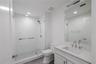 Bathroom 2 offers a sleek, contemporary design with a frameless glass-enclosed walk-in shower featuring large-format white tile and a mosaic tile show