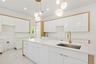 Kitchen with hanging light fixtures, white cabinetry, light stone counters, modern cabinets, and recessed lighting