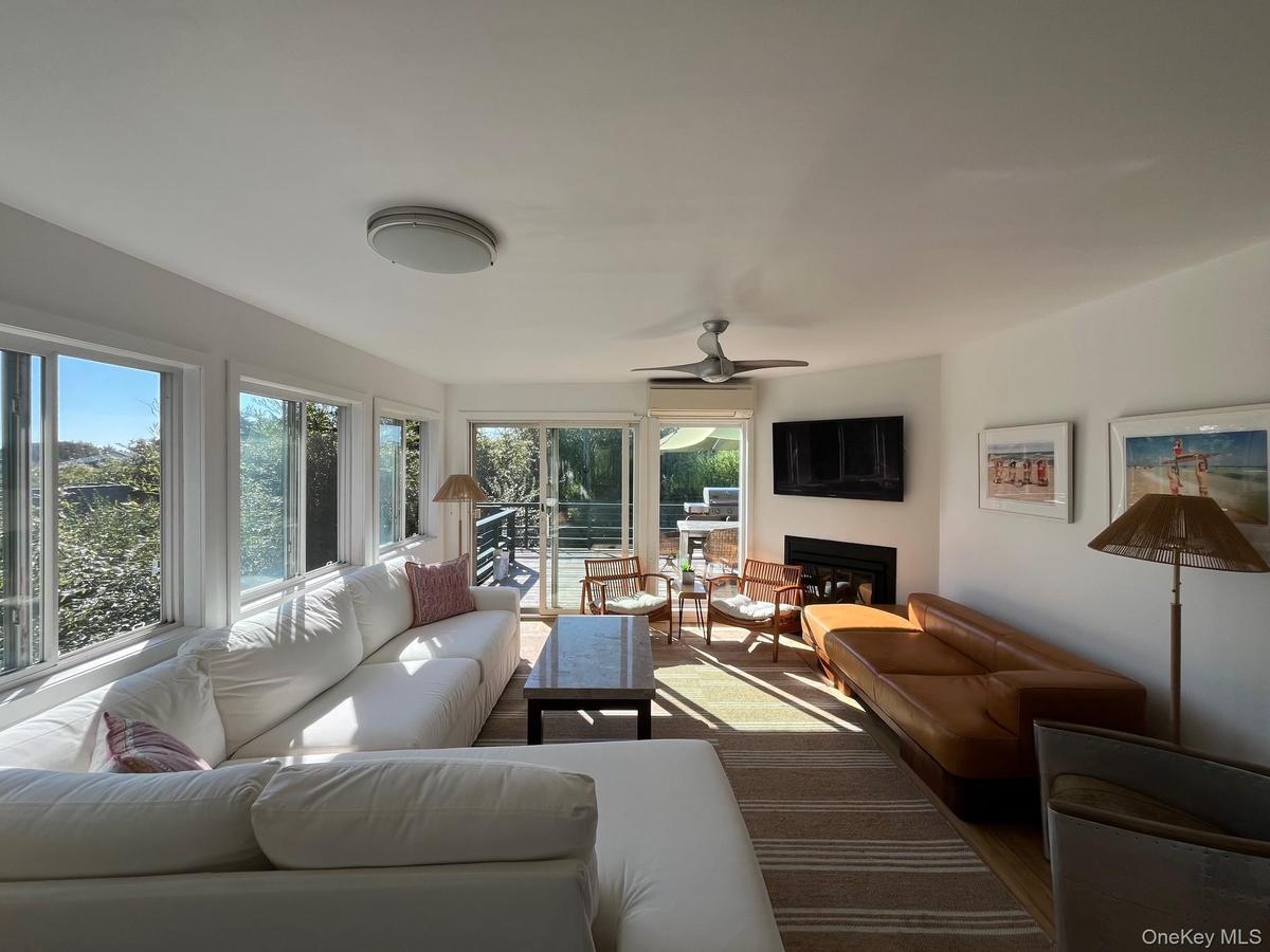 Living room featuring a glass covered fireplace, a ceiling fan, and wood finished floors
