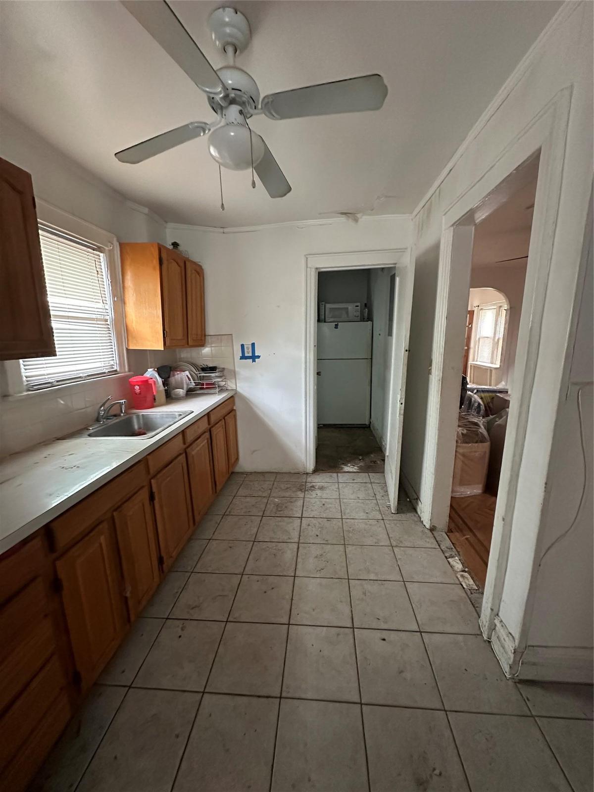 Kitchen featuring tasteful backsplash, light countertops, ceiling fan, light tile patterned floors, and brown cabinets