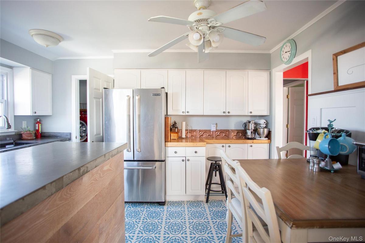 Kitchen featuring high end refrigerator, ornamental molding, white cabinets, and ceiling fan