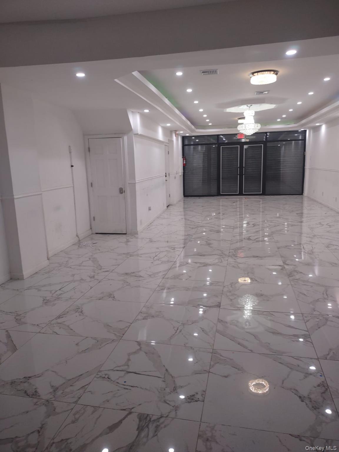 Corridor with light marble finish floors, recessed lighting, and a raised ceiling