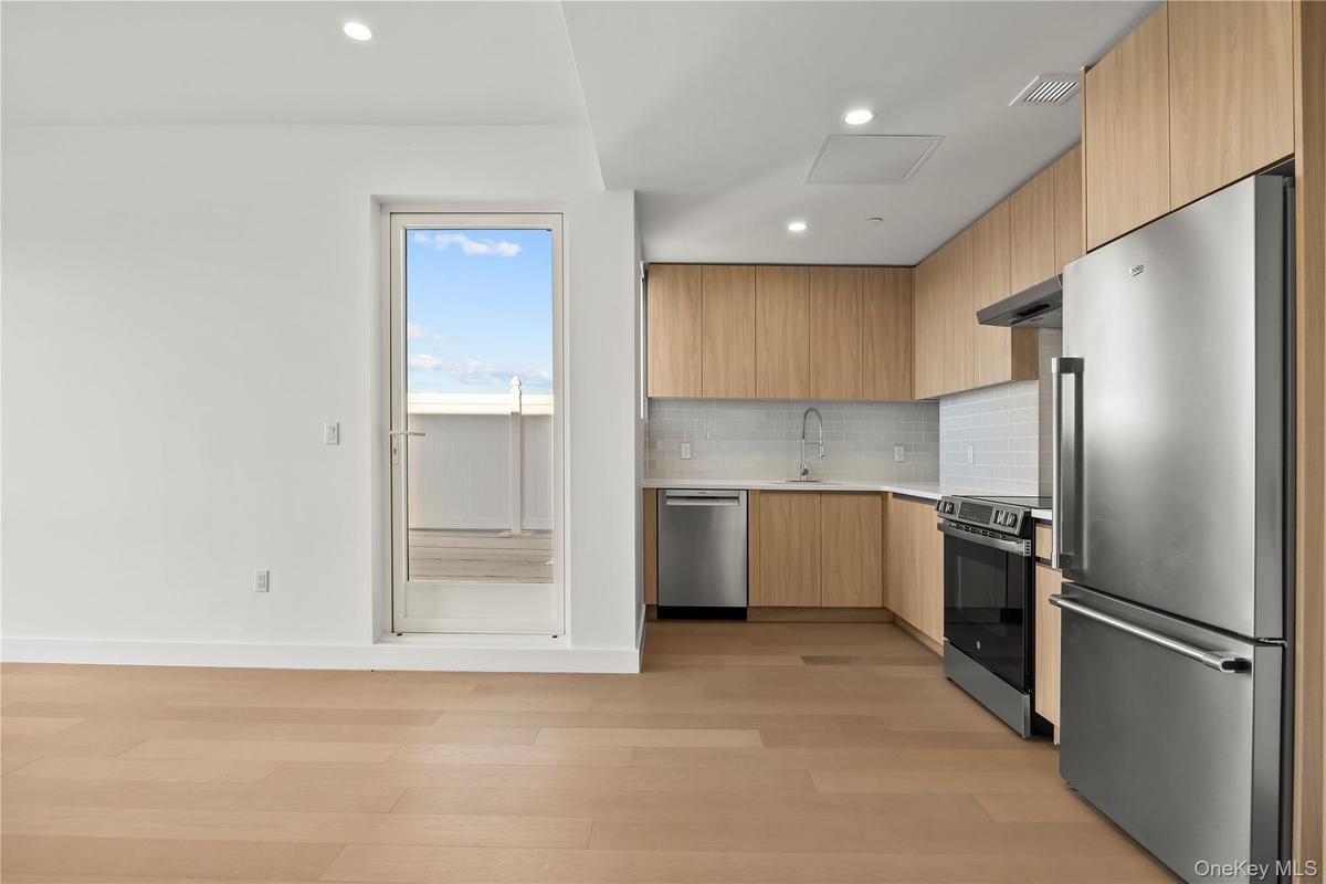 Kitchen with modern cabinets, appliances with stainless steel finishes, recessed lighting, light wood-type flooring, and light brown cabinets