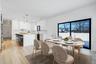 Bright dining space positioned beside kitchen and living room featuring wet bar and large glass sliders, offering great natural light and easy access