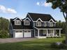 Two-story residence featuring dormer windows, a covered front porch, an attached two-car garage, and a paved driveway