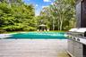View of pool featuring a covered pool, a gazebo, view of scattered trees, and a wooden deck