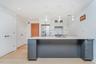 Kitchen with white cabinets, backsplash, gray cabinetry, stainless steel fridge with ice dispenser, and light wood-type flooring