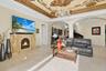Ornate stone electric fireplace, intricate moldings on ceiling accented by chandeliers.