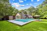 View of pool featuring a lawn, a deck, and view of wooded area