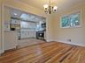 Open-concept dining area with wood-finish flooring, crown molding, and a chandelier, opening to a kitchen featuring white cabinetry, a skylight, and s