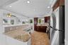 Kitchen featuring stainless steel appliances, decorative backsplash, light stone finish flooring, recessed lighting, and ornamental molding