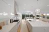 Kitchen featuring white cabinets, a healthy amount of sunlight, a spacious island, and sink
